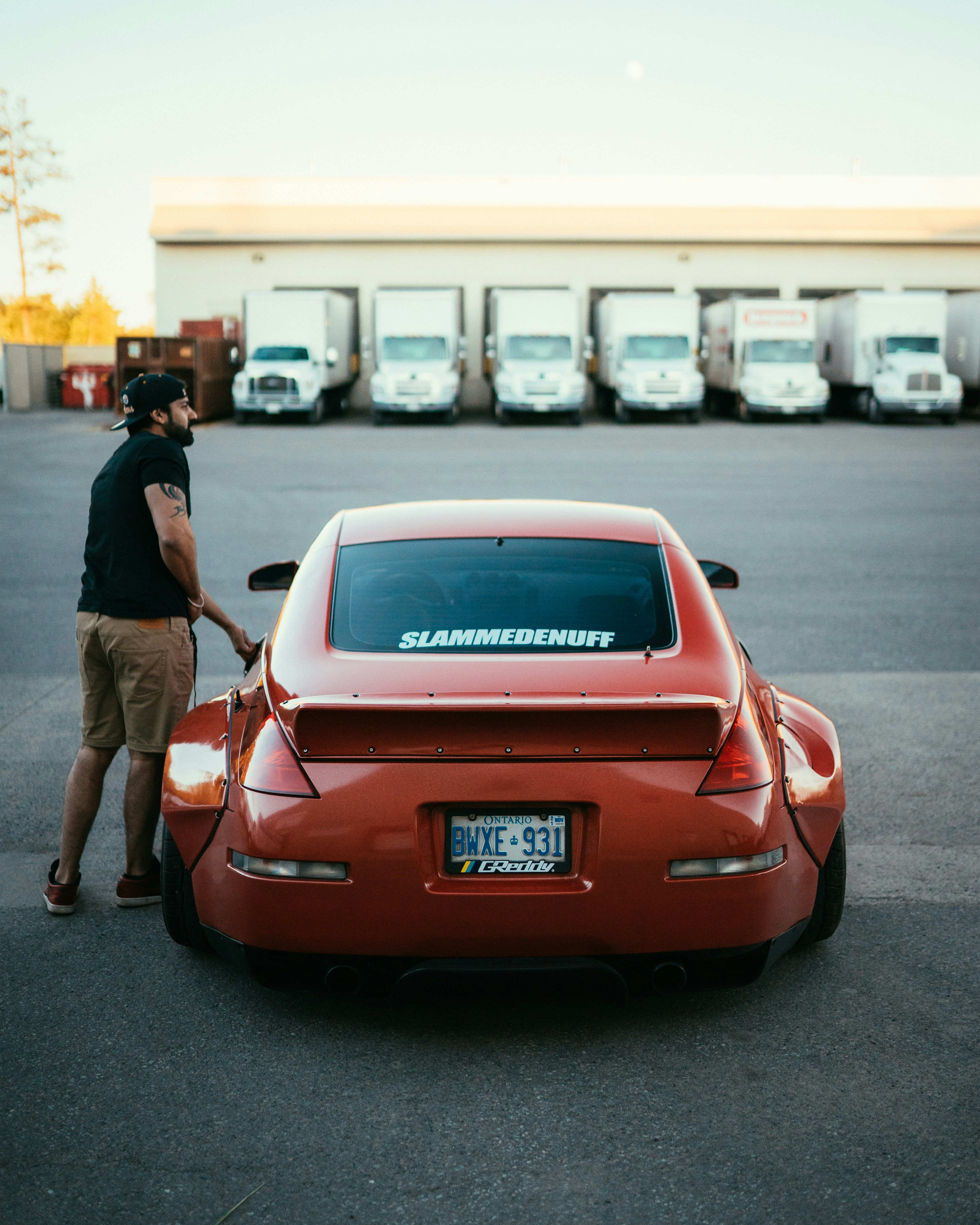 man in black t-shirt standing beside red car